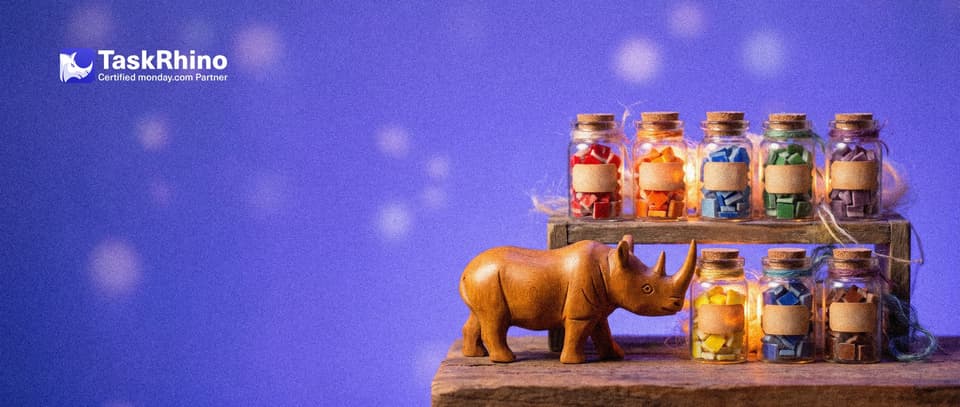 A small wooden rhino stands before a short wooden shelf of seven small, different glass jars, each holding differently shaped coloured tiles, nudging one jar forward with its horn.