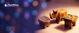 A small wooden rhino stands between two small pedestals, looking from one to the other: on one a clear glass block divided into a grid of tiny cells, on the other a tidy board of coloured tiles.