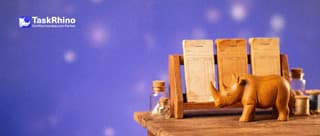 A small wooden rhino chooses between three different paper form pads standing in a small wooden rack, like at a stationery counter.