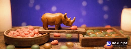 A small wooden rhino carries items from a round ceramic dish of smooth coral-pink pebbles into a tidy board of coloured tiles, nothing dropped on the way.