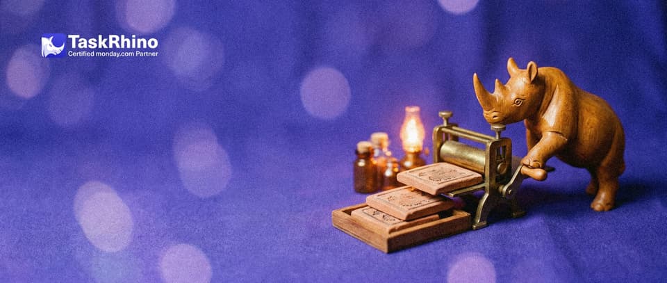 A small wooden rhino turns the crank of a tiny brass printing press that lays out three identical small tile boards in a neat stack.