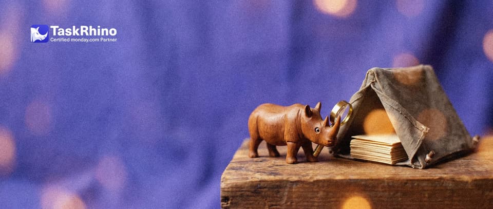 A small wooden rhino inspects a single small canvas tent through a brass magnifying glass; inside the tent sits a tidy stack of paper message cards.