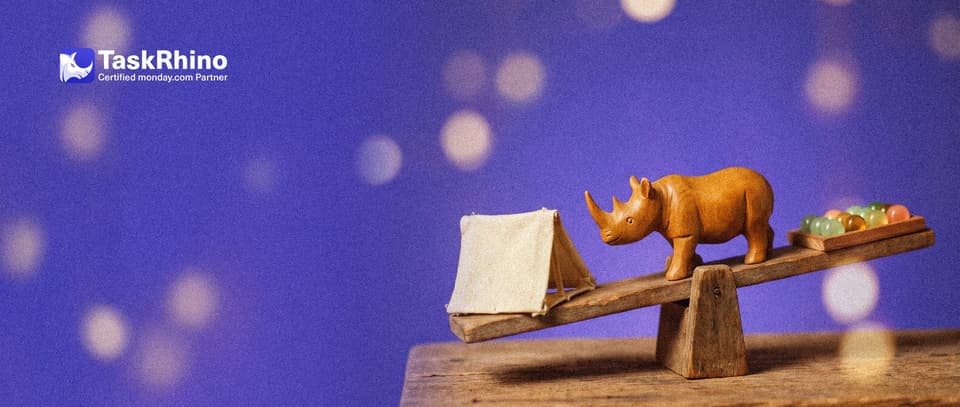 A small wooden rhino stands at the middle of a level wooden seesaw: a small simple canvas tent on one end, a tidy board of coloured tiles on the other.