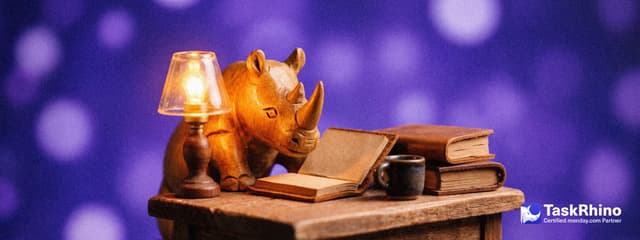 A small wooden rhino reads by lamplight at a little desk stacked with leather-bound blocks, a cup of tea beside it.