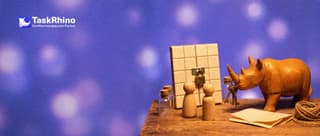 A small wooden rhino hands small brass keys of different sizes to wooden peg figures in front of a tile board with a little lock.
