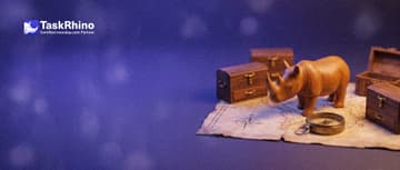 A small wooden rhino stands on an unfolded paper map with several small tool chests placed on it like towns, a brass compass at its feet.