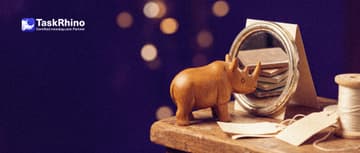 A small wooden rhino examines a small hand mirror on a paper form card that reflects a column of tiles from a board; one edge of the mirror is chipped.