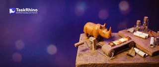 A small wooden rhino turns a hand crank on a miniature conveyor belt that carries glowing tiles from one small board to another.