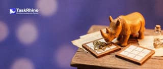 A small wooden rhino compares two identical tile boards: the original has small clockwork gears attached and turning, the copy has none.