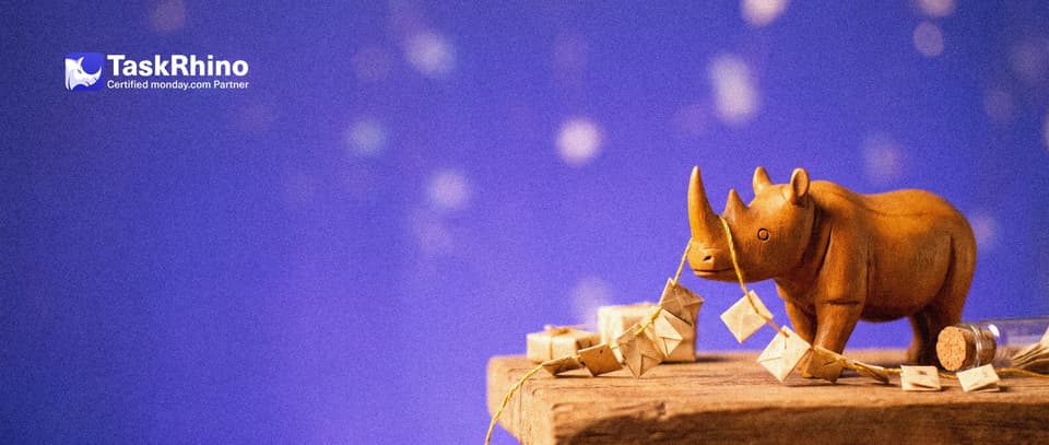 A small wooden rhino holds the end of a single long golden string with many tiny envelopes threaded on it like a garland.