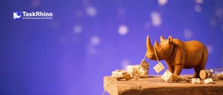 A small wooden rhino holds the end of a single long golden string with many tiny envelopes threaded on it like a garland.