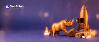 A small wooden rhino picks one of several small tool chests to load into a tiny wooden rocket on a launch pad.