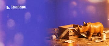 A small wooden rhino measures an open wooden crate with a tailor's cloth tape, like a fitting.