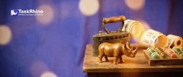 A small wooden rhino stands between a heavy old iron and brass machine trailing a long paper roll of bars and a tidy board of coloured tiles.