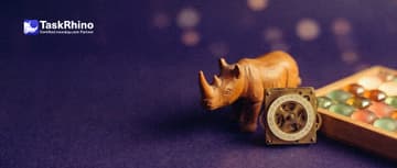 A small wooden rhino watches a small brass clockwork calendar wheel turning by itself next to a tidy board of coloured tiles.