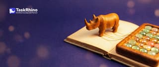 A small wooden rhino stands on the page of an open notebook that is joined by golden threads to a tidy board of coloured tiles, tying the threads together.