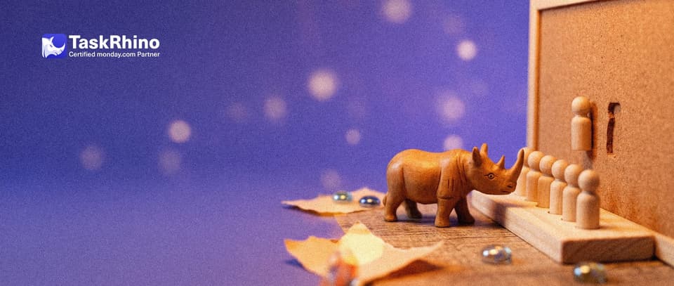 A small wooden rhino looks at a column of tiny wooden peg figures standing in slots on a paper form card; on a public notice board behind, the same slot is empty.