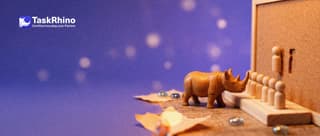 A small wooden rhino looks at a column of tiny wooden peg figures standing in slots on a paper form card; on a public notice board behind, the same slot is empty.
