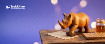 A small wooden rhino presses a small hand-made wooden stamp onto a paper form card, copying marks from a nearby tile board.
