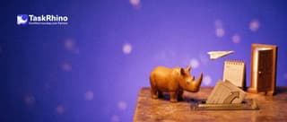 A small wooden rhino watches a paper form card slide into a brass slot and come out as a paper airplane flying toward a small desk calendar and a little open door.