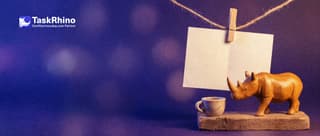 A small wooden rhino steps away for a teacup break from a half-filled paper form card hung by a wooden clothes peg on a little string.