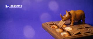 A small wooden rhino lifts one of several small fold-out paper flaps on a form card, some folded open and others closed.