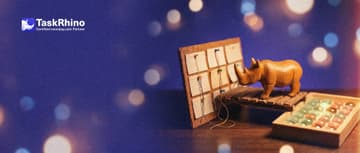 A small wooden rhino stands on a tiny wooden bridge between a cork board of index cards in columns and a tidy board of coloured tiles.