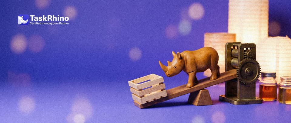 A small wooden rhino stands at the middle of a wooden seesaw: a light open wooden crate on one end, a heavy brass machine on the other.