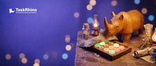 A small wooden rhino lifts a small cloth off a tidy board of coloured tiles, as if unveiling it.
