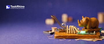 A small wooden rhino watches a small chain reaction run on its own: a glass marble, a lever, a row of dominoes, ending with a tile glowing green on a board.