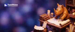 A small wooden rhino measures distances with brass dividers on a small wooden map table lined with tiny different tool chests.