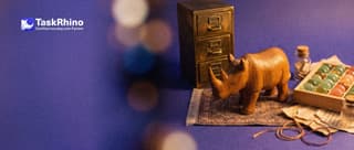A small wooden rhino stands on a rug between a heavy formal brass filing cabinet and a tidy board of coloured tiles.